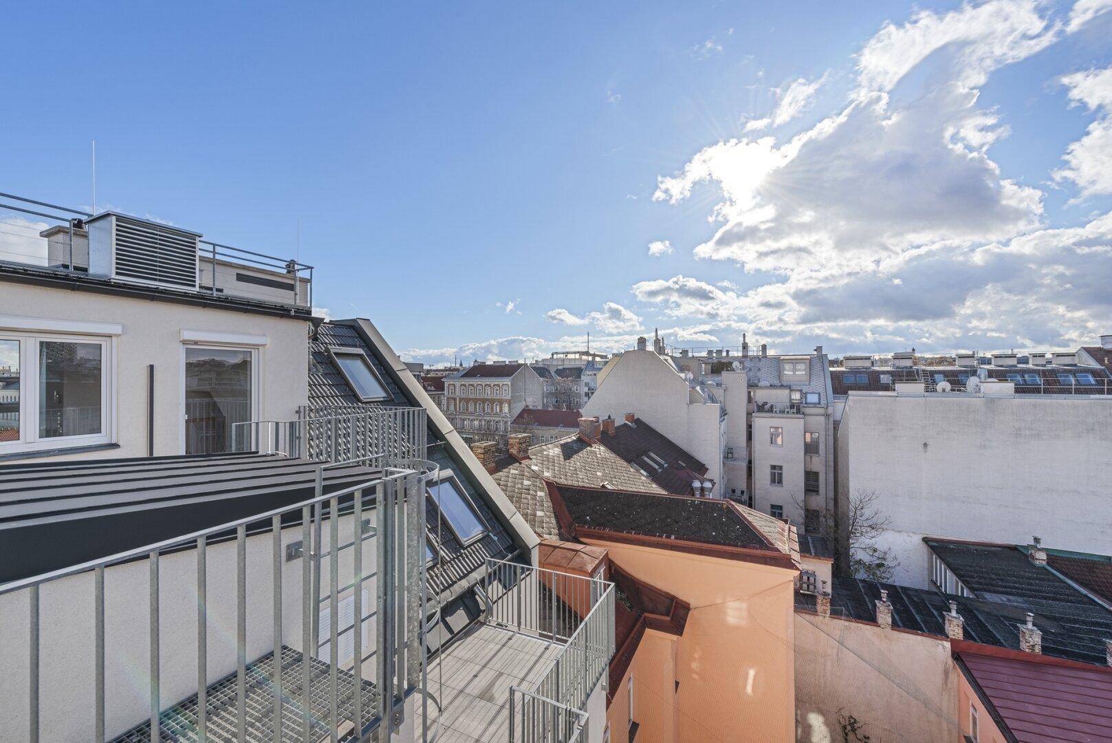 Panoramablick von der Dachterrasse über die historischen Dächer der Stadt unter strahlend blauem Himmel.
