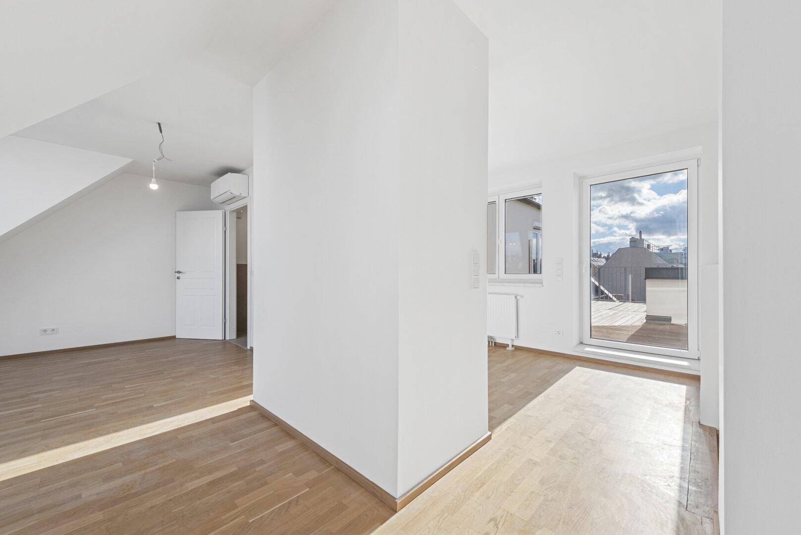 Heller Wohnbereich mit Holzboden und großem Terrassenzugang, der viel Tageslicht hereinlässt.