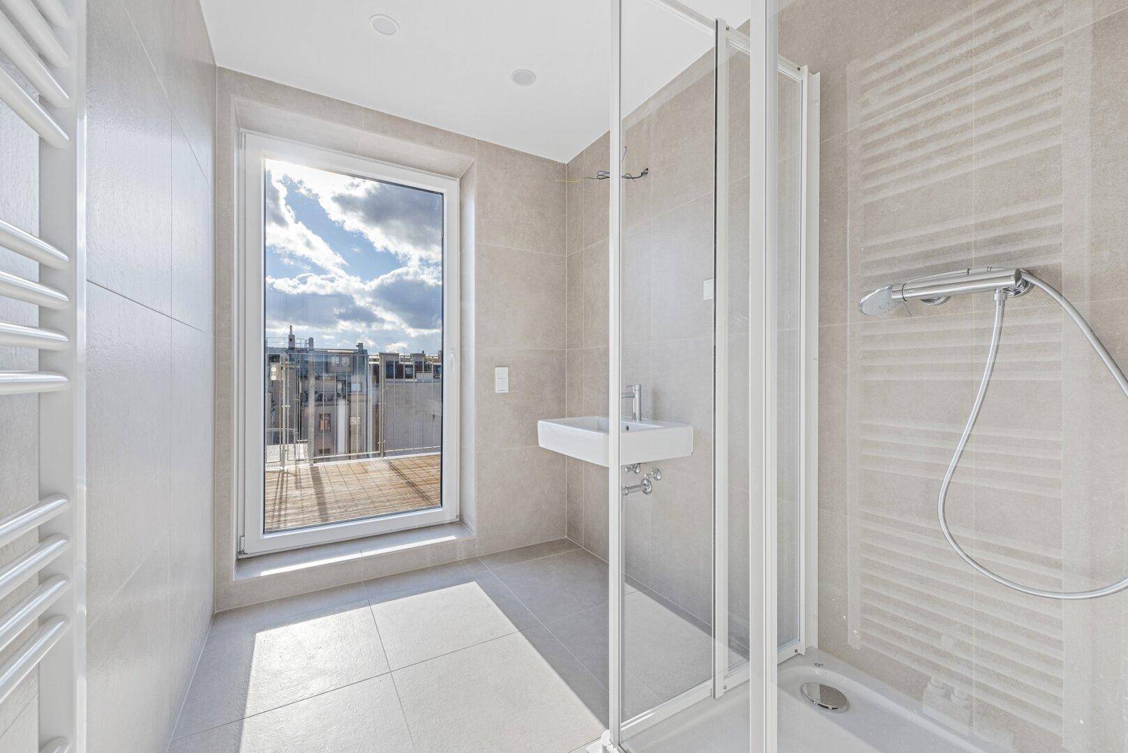 Modernes Badezimmer mit Dusche, Waschbecken, beheiztem Handtuchhalter und Terrassenzugang mit Stadtblick.