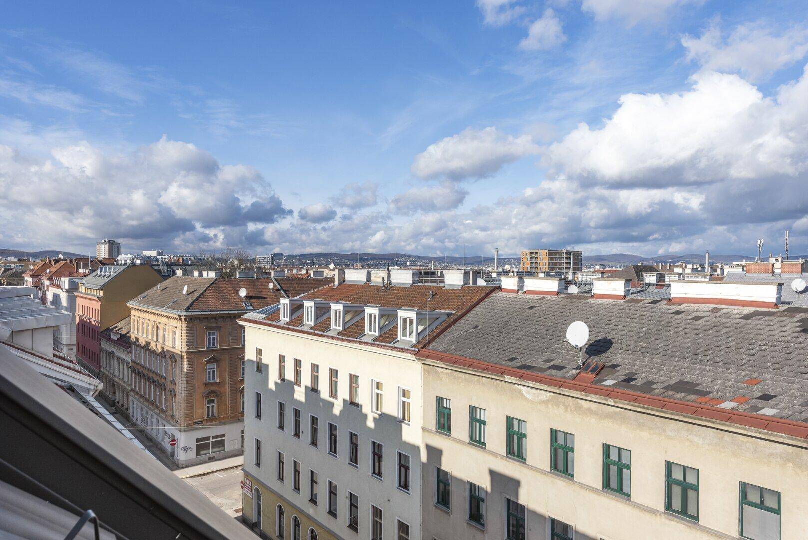 Weitläufiger Panoramablick über die Dächer der Stadt und umliegende Gebäude unter blauem Himmel.
