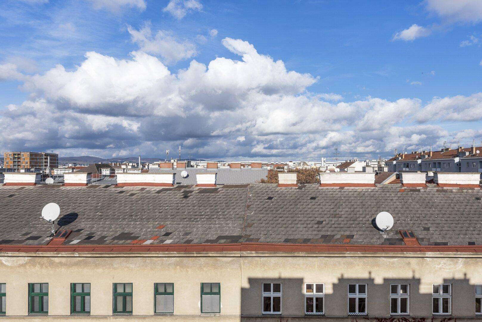 Aussicht über die Dächer der Stadt mit Satellitenschüsseln und dem Horizont im Hintergrund.