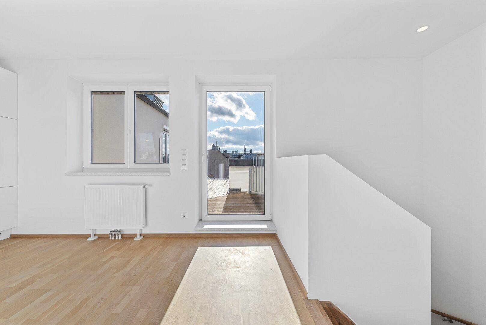 Heller Wohnbereich mit Holzboden und großem Terrassenzugang, der viel Tageslicht hereinlässt.