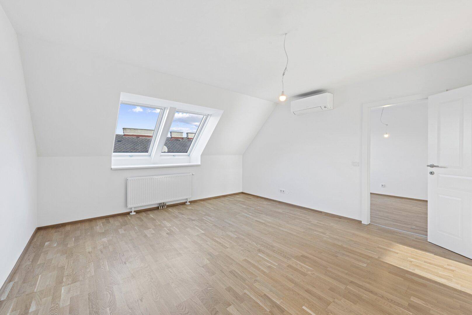 Geräumiges Zimmer mit Parkettboden, Dachfenstern und Klimaanlage, das viel Tageslicht erhält.