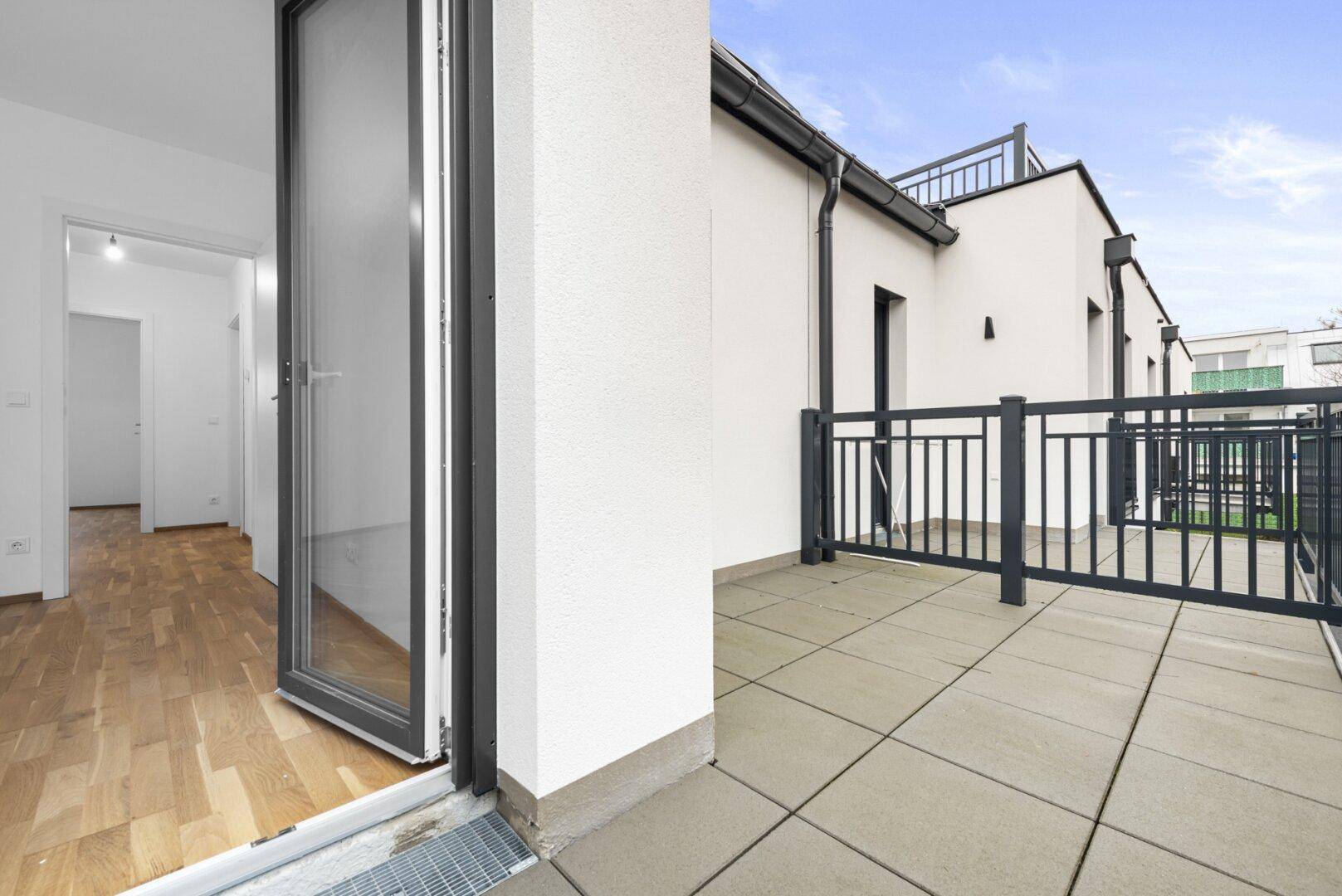 Geräumiger Balkon mit Fliesenboden und Metallgeländer, zugänglich vom Innenbereich.