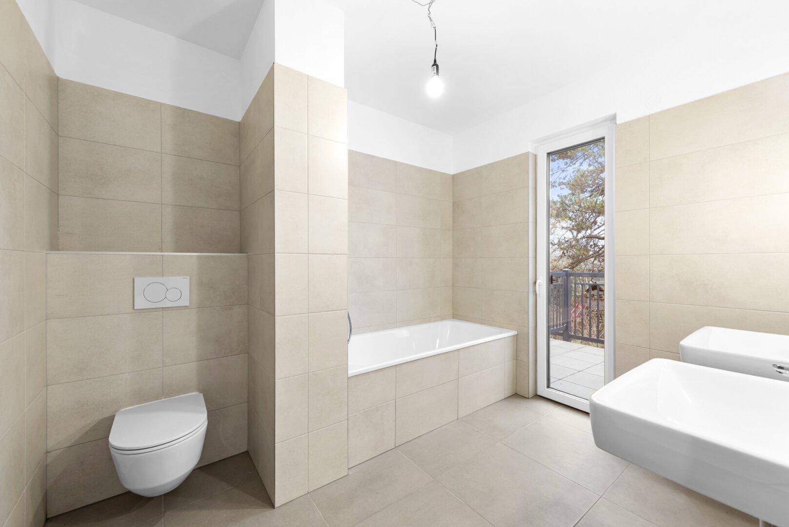 Modernes Badezimmer mit Badewanne, WC und Zugang zu einem Balkon.
