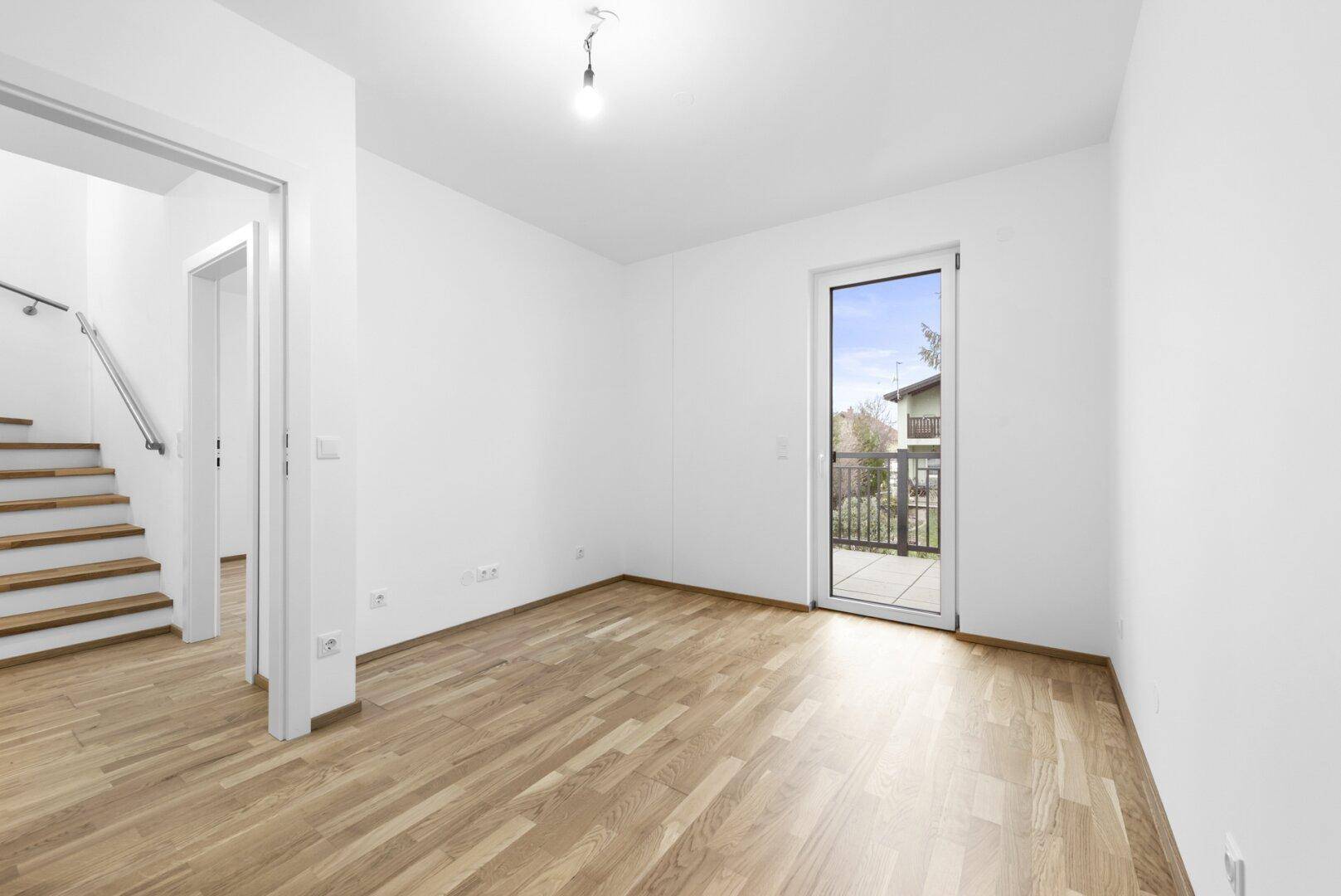 Helles Zimmer mit Holzboden und Balkonzugang, ideal als Schlaf- oder Arbeitszimmer.