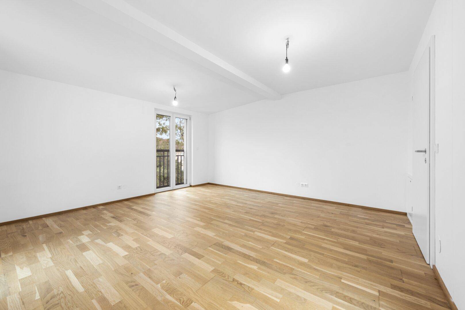Großes, helles Zimmer mit Holzboden und mehreren Zugängen zu Balkonen.