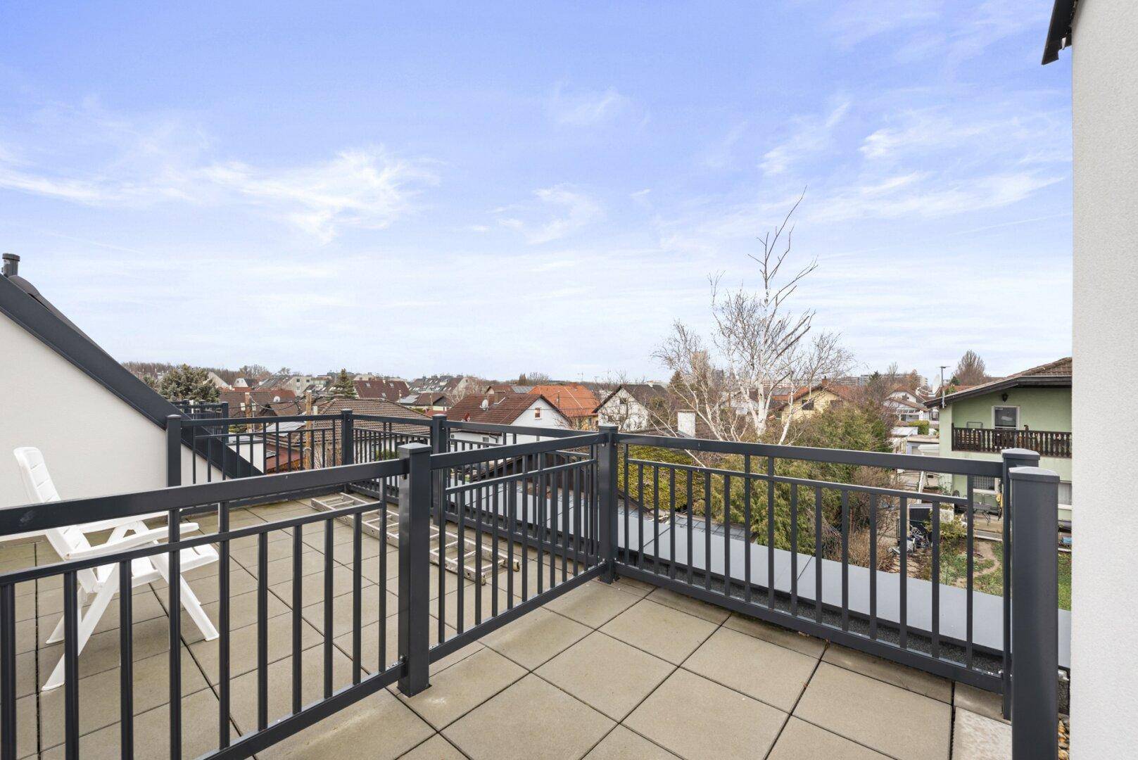 Weitläufige Dachterrasse mit Fliesenboden und Panoramablick über die Nachbarschaft.