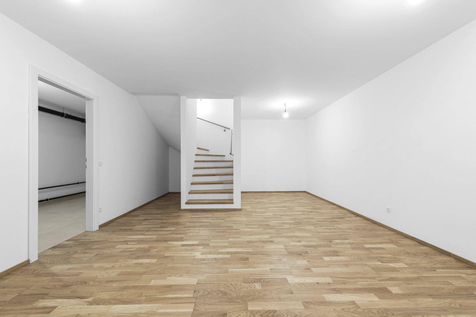 Großer Kellerraum mit Holzboden und Treppenzugang, bietet viel Stauraum.