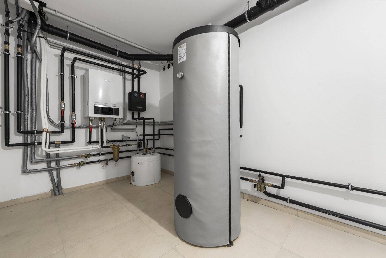 Technikraum mit Warmwasserspeicher und sichtbaren Installationen für die Haustechnik.