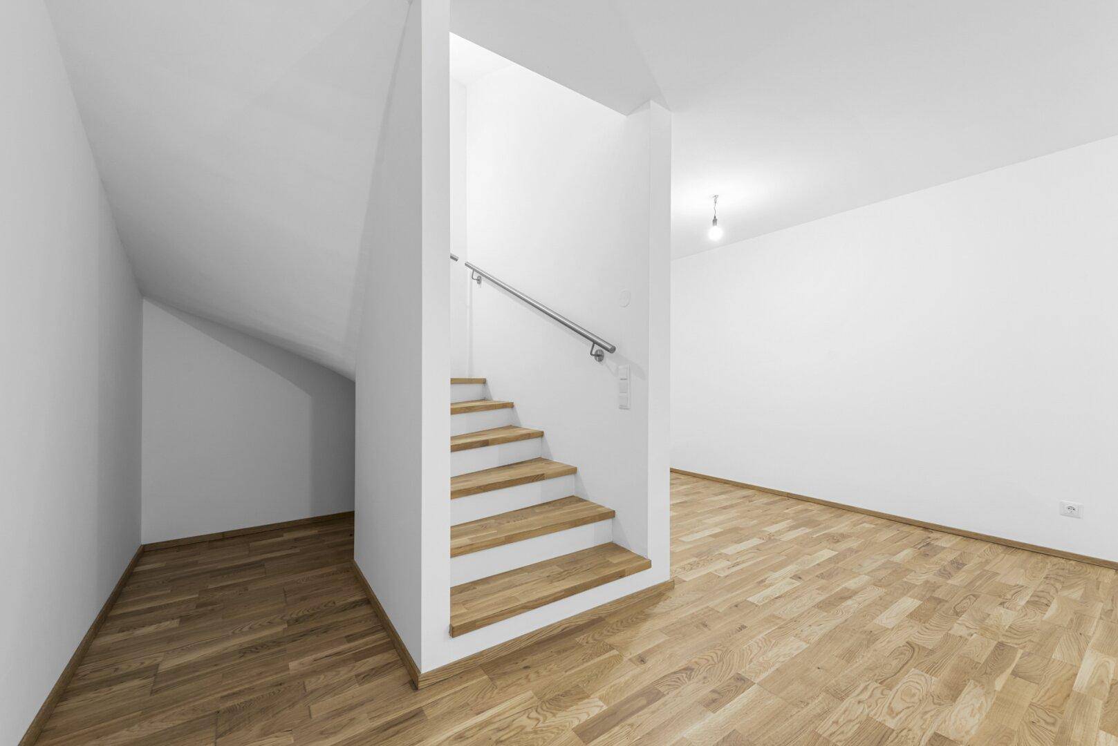 Heller Wohnbereich mit Holzboden, Treppe und Dachschräge, bietet viel Potenzial.