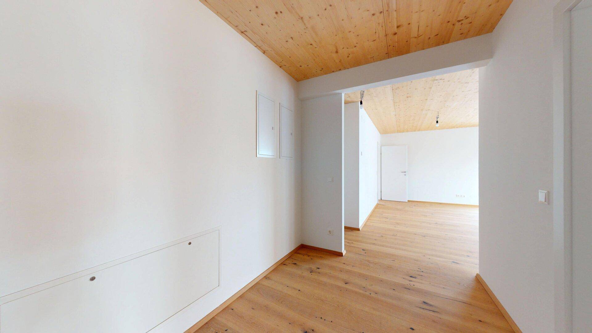 Geräumiger Flur mit Holzboden und Holzbalkendecke, führt zu weiteren Zimmern der Wohnung.