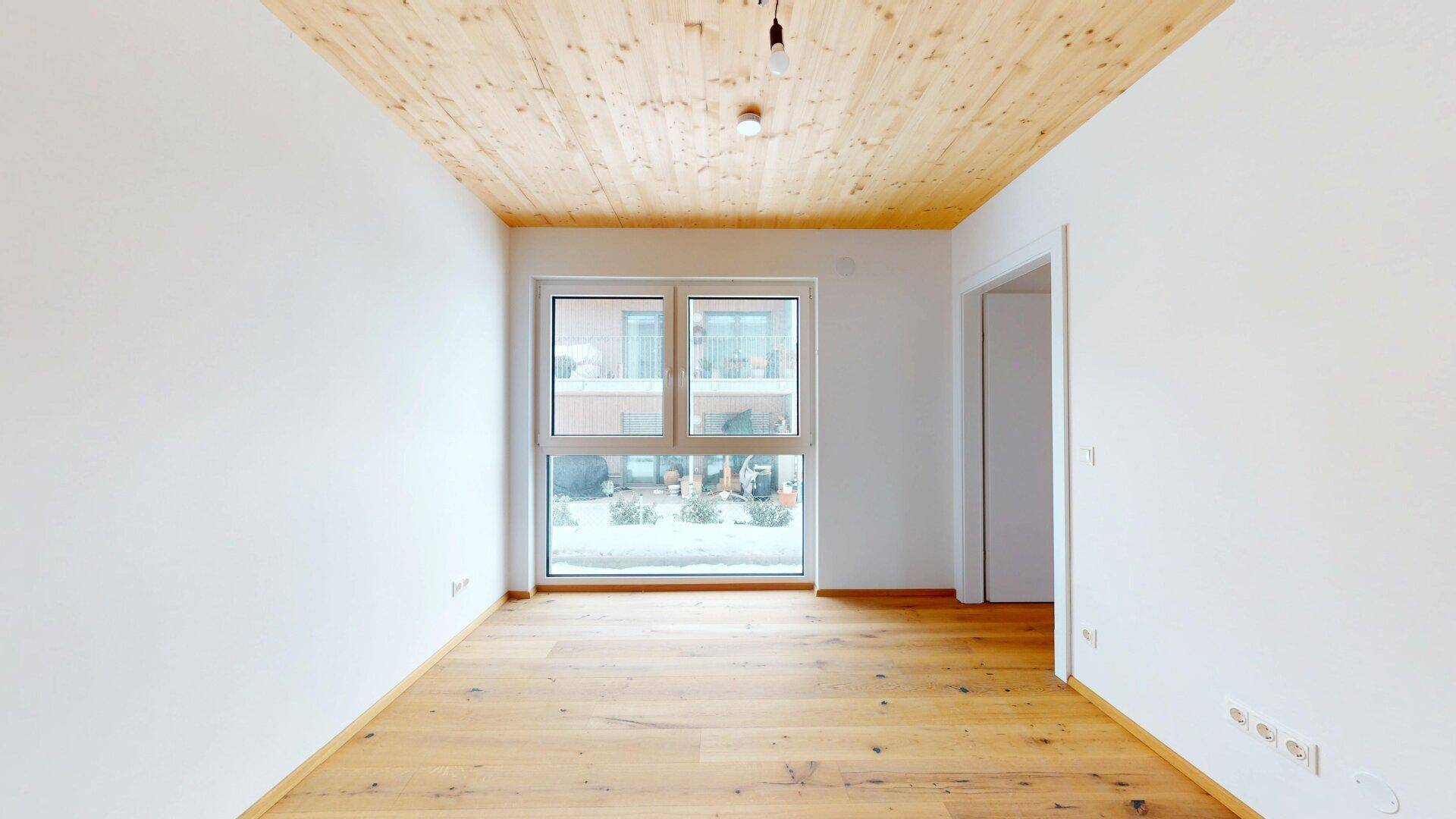 Helles Zimmer mit Holzboden und großem Fenster, ideal als Schlaf- oder Arbeitszimmer.
