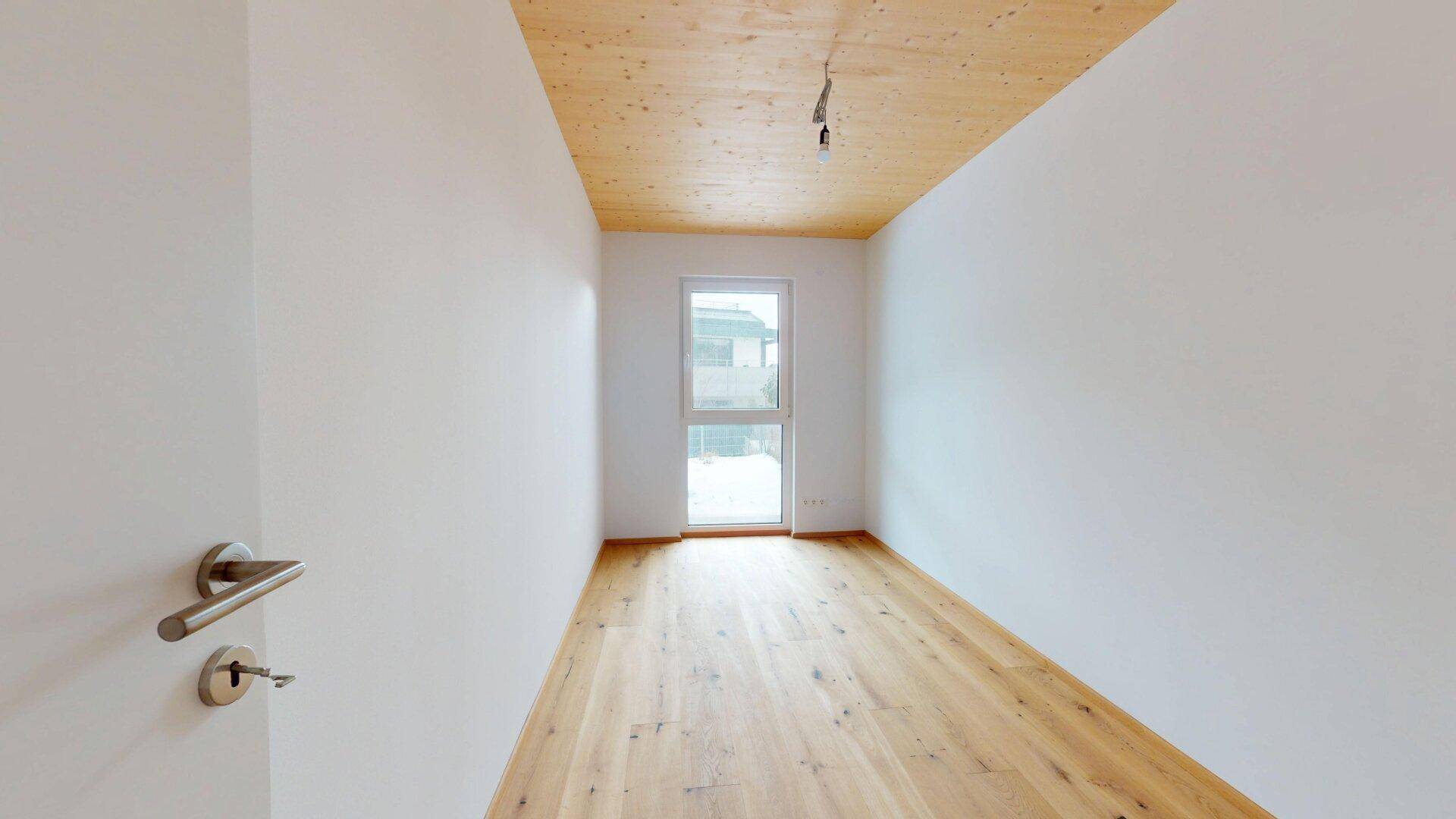 Kleines, helles Zimmer mit Holzboden und Zugang zum Außenbereich, vielseitig nutzbar.