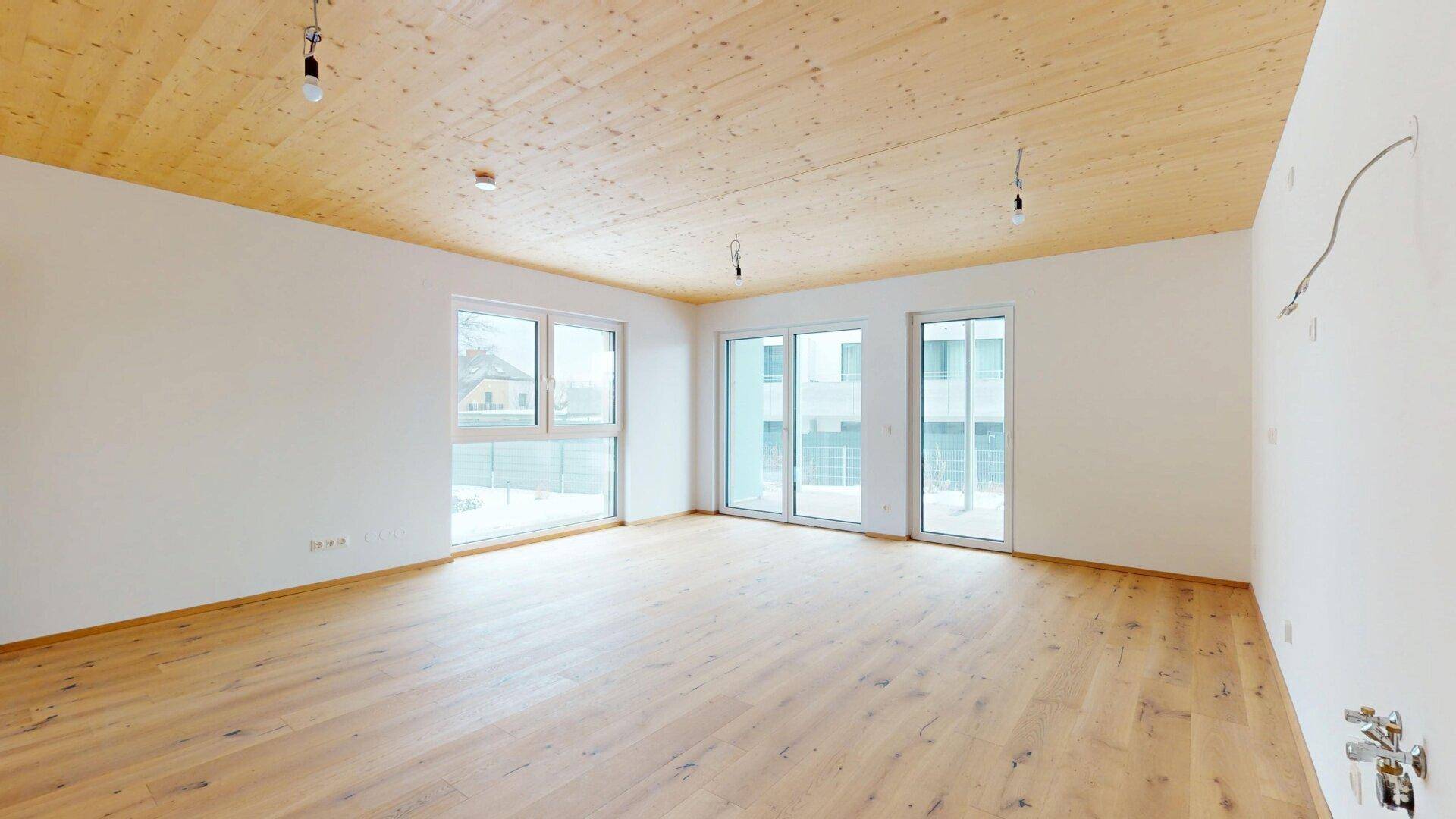 Großer, heller Raum mit Holzboden und Zugang zu einem Außenbereich, ideal für offenes Wohnen.
