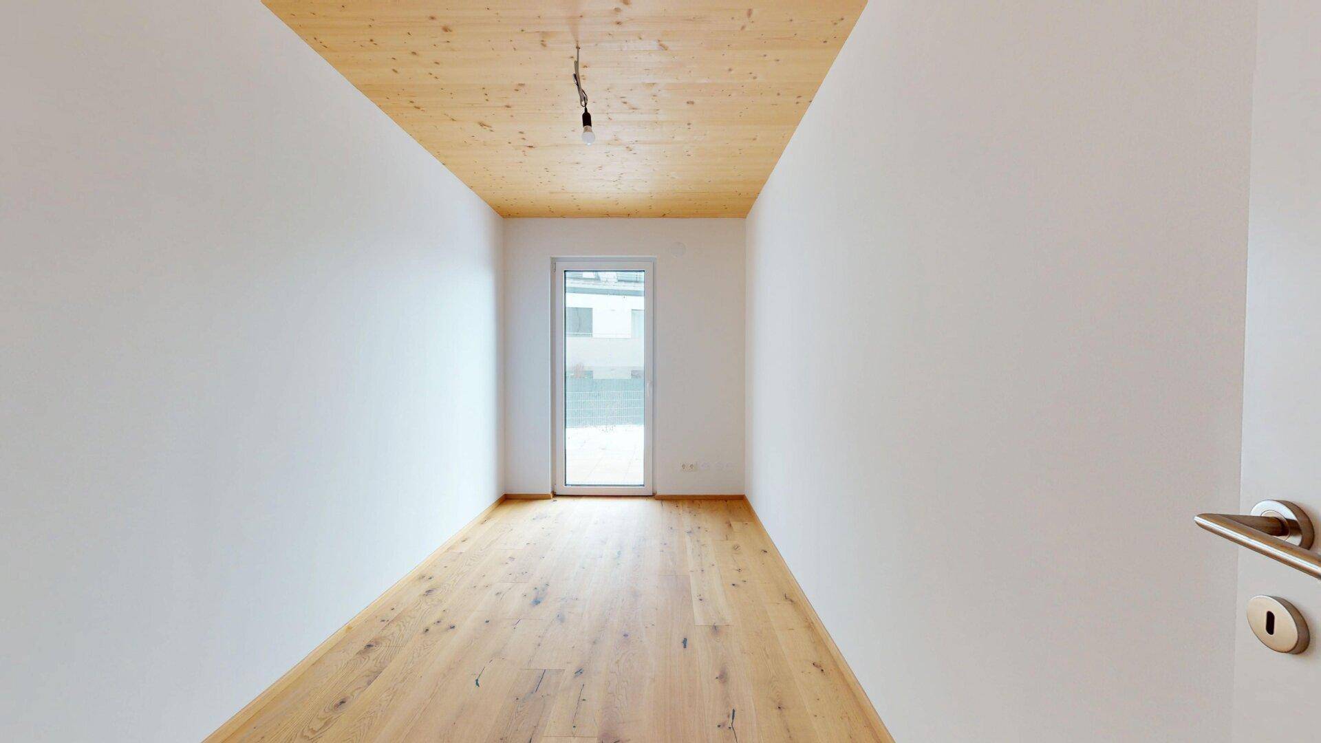 Helles Zimmer mit Holzboden und Zugang zum Außenbereich, ideal als Kinder- oder Gästezimmer.