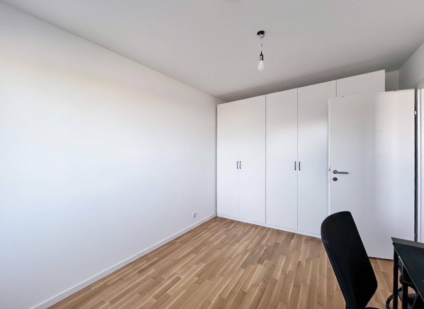 Schlafzimmer mit Parkettboden und praktischen Einbauschränken.