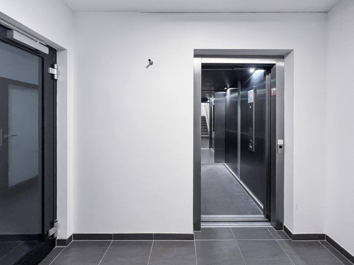 Heller Flur mit Aufzug und Zugang zu den Wohneinheiten.