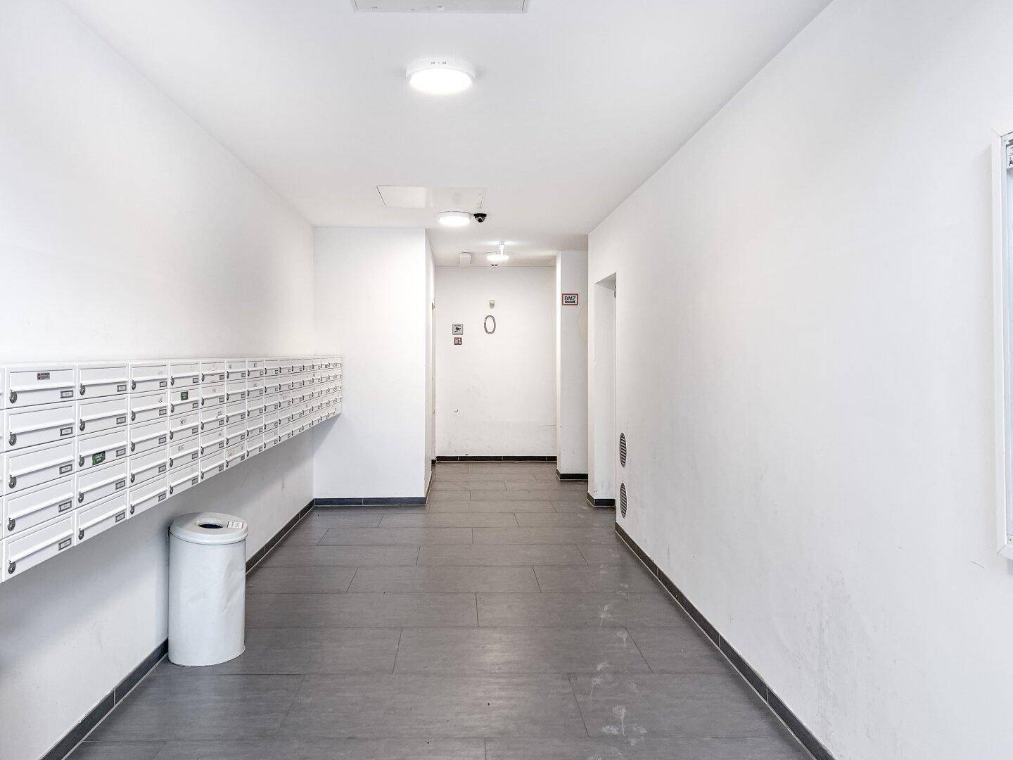 Geräumiger Eingangsbereich mit Briefkästen und Fliesenboden.