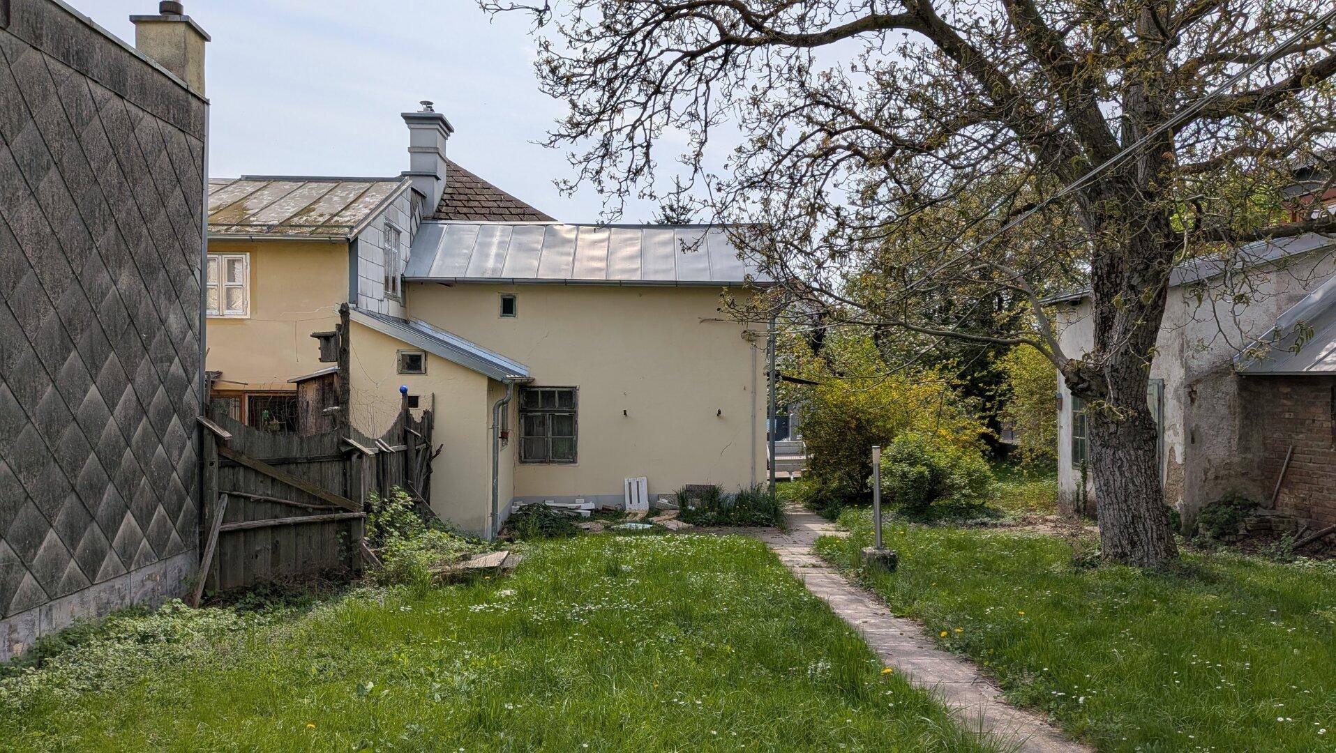 Rückseite des Hauses mit einem Gartenpfad und einer Rasenfläche.