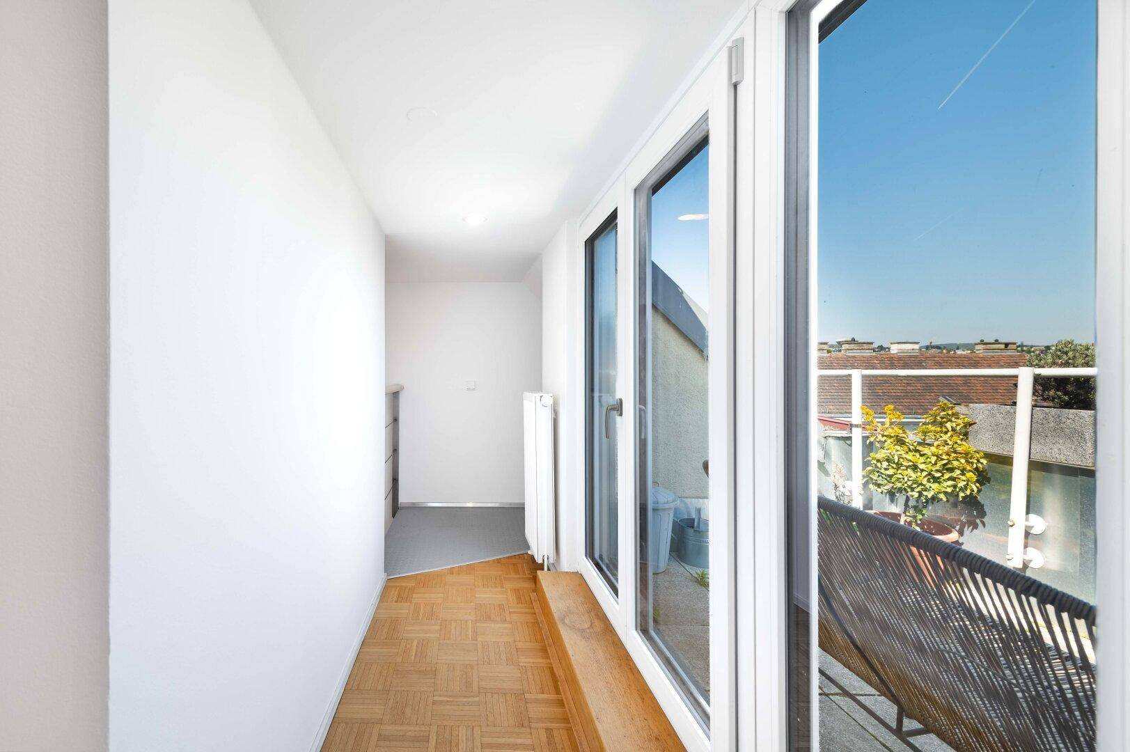 Lichtdurchfluteter Flur mit Terrassenzugang und weitem Blick über die Stadt.