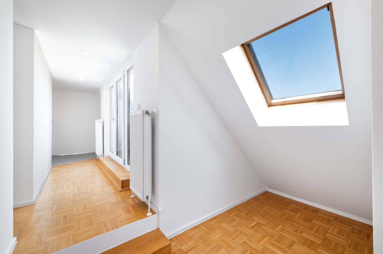 Heller Flur im Dachgeschoss mit Parkettboden und einem großen Dachfenster.