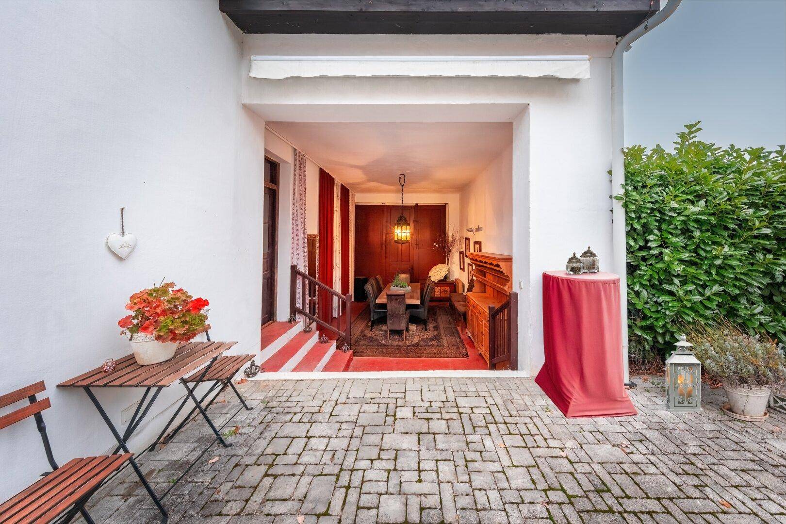 Offener Essbereich mit großem Holztisch und Blick auf den gepflasterten Innenhof.
