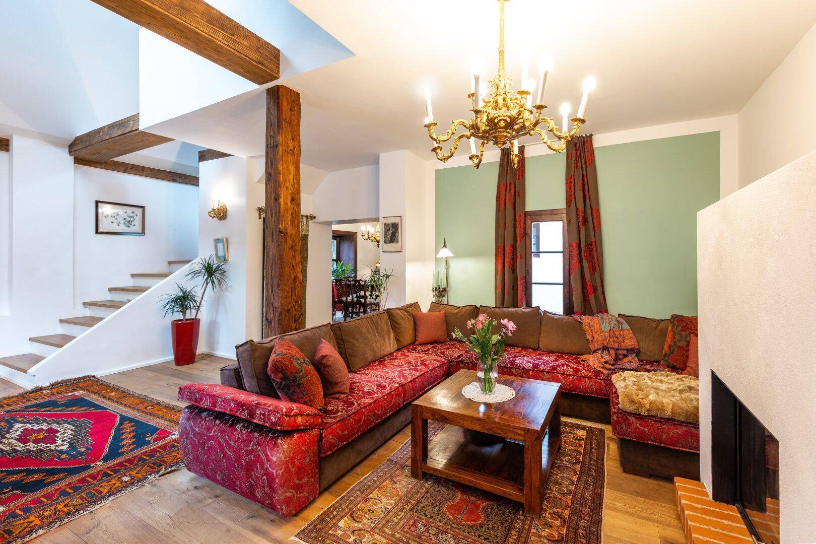 Komfortables Wohnzimmer mit großer Eckcouch, Kamin und Blick auf die Treppe.