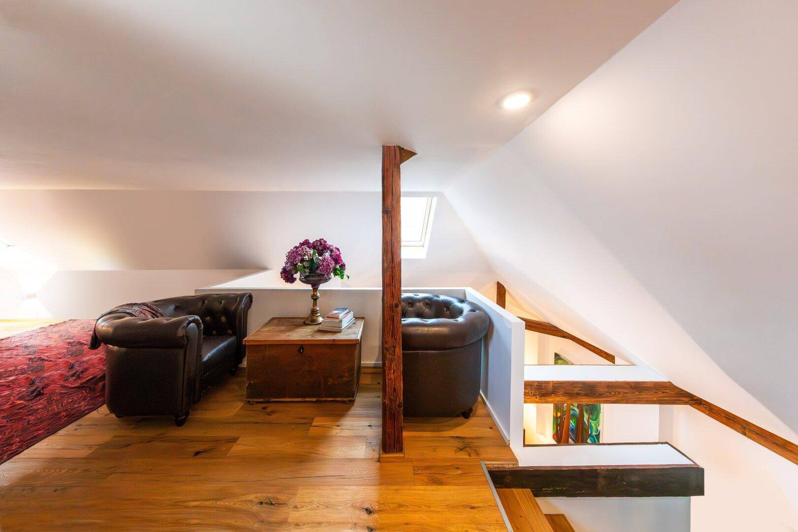 Gemütlicher Lounge-Bereich im Dachgeschoss mit Ledersesseln und Holzboden.
