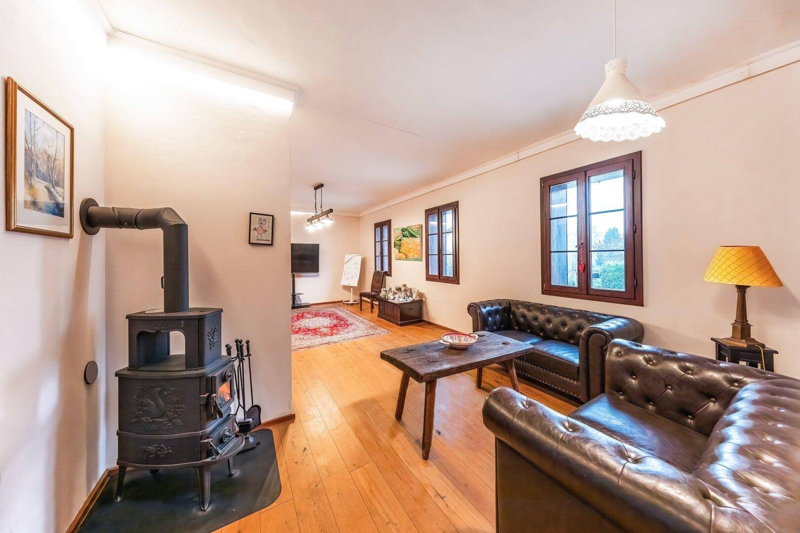 Rustikales Wohnzimmer mit Holzofen, Ledersofas und Holzboden.