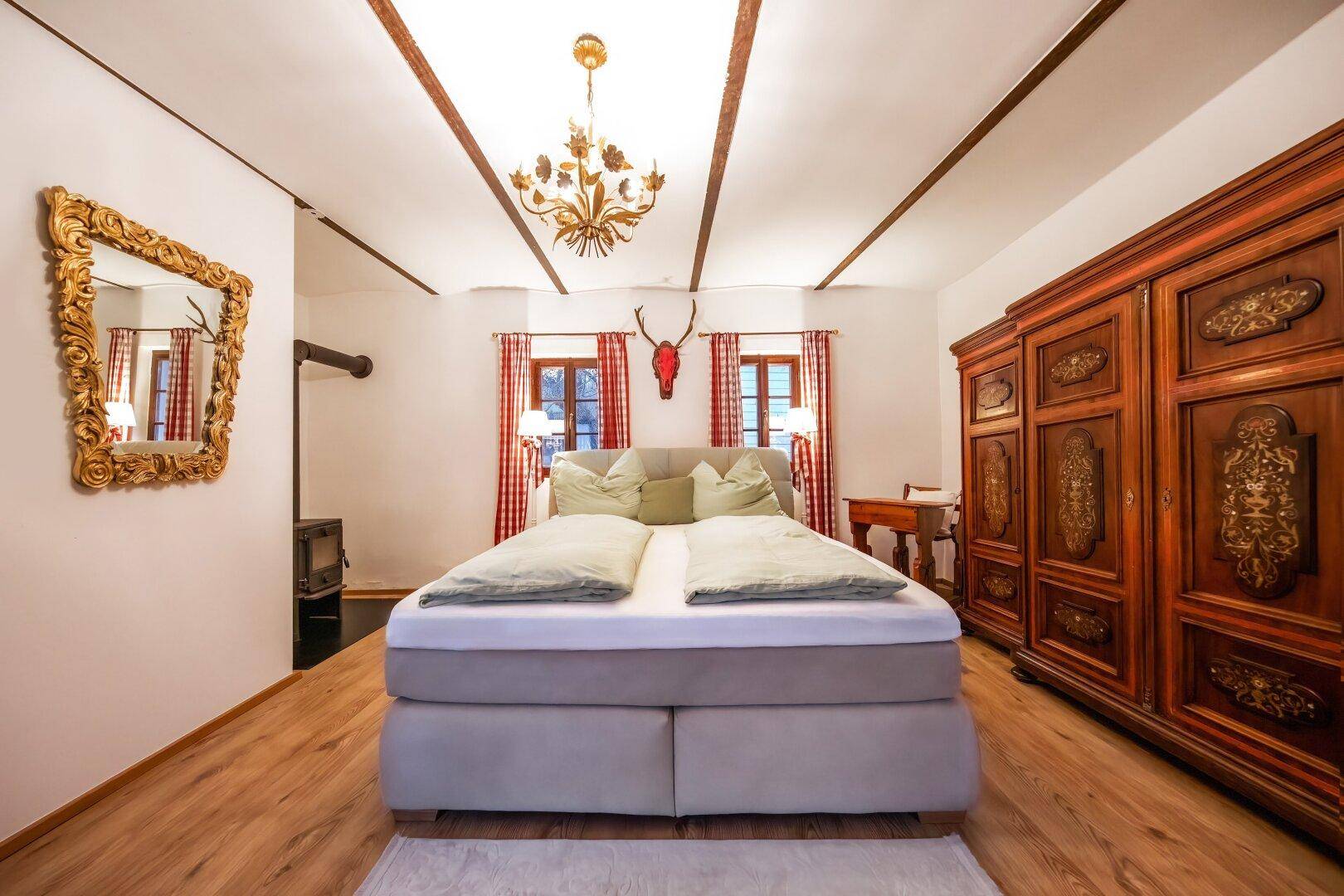Gemütliches Schlafzimmer mit Doppelbett, Holzbalken an der Decke und traditionellem Kleiderschrank.