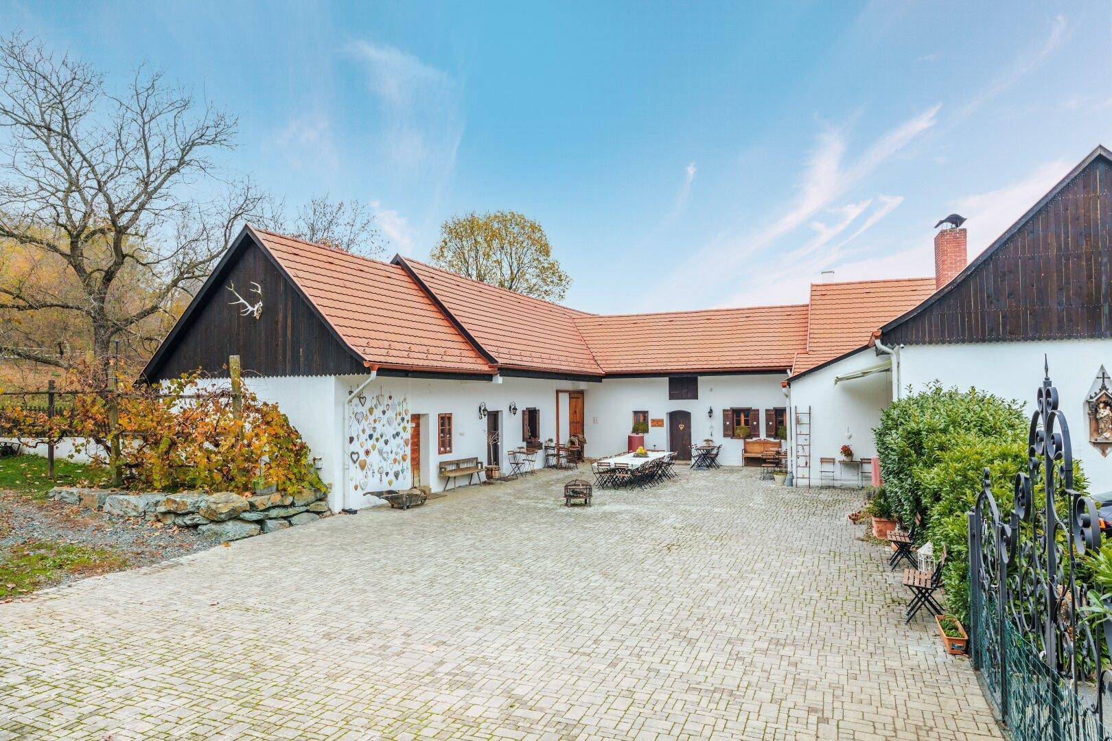 Weitläufiger Innenhof mit traditionellen Gebäuden, gepflastertem Boden und Blick auf die umliegende Landschaft.