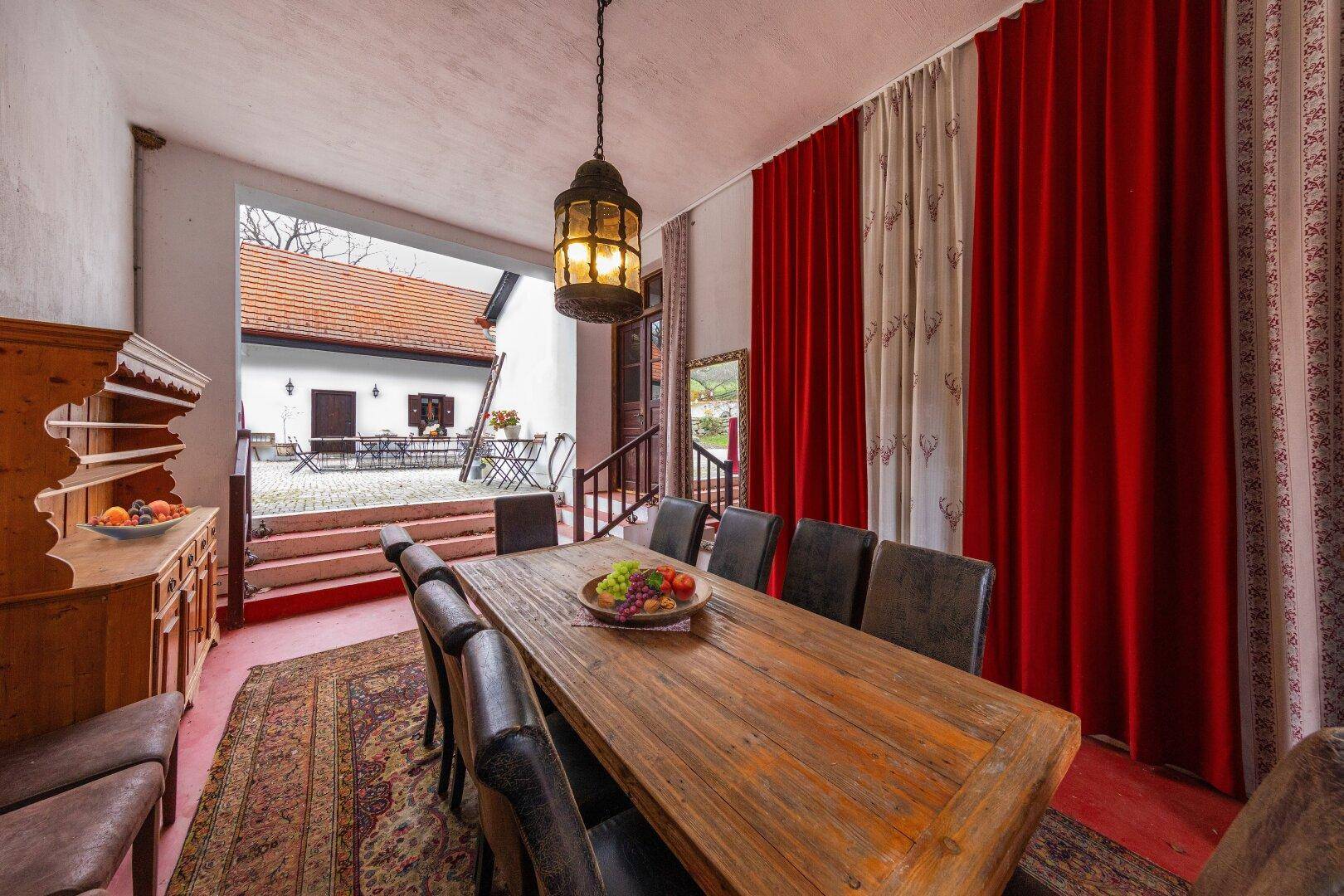 Geräumiger Essbereich mit großem Holztisch, Ledersesseln und Blick auf den Innenhof.