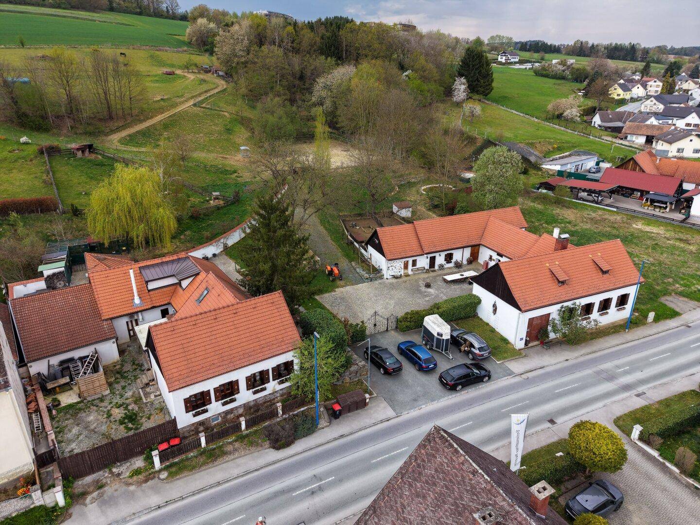 Luftaufnahme des Anwesens mit Gebäuden, Parkplätzen und angrenzender Straße.