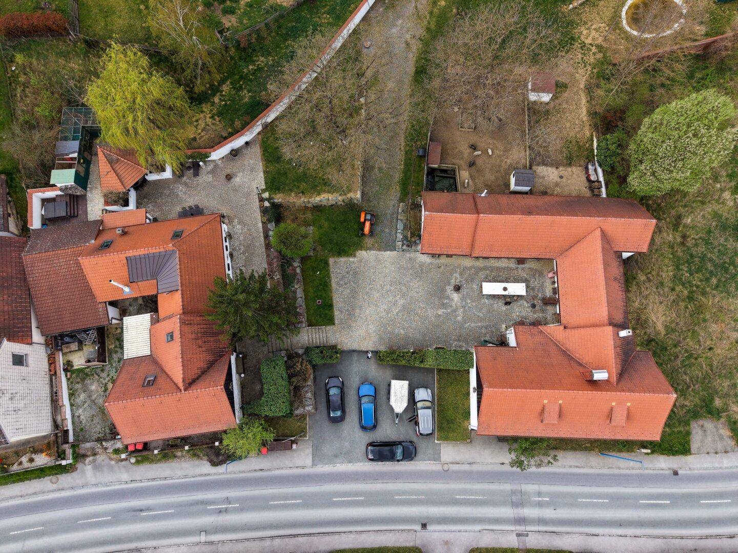 Draufsicht des Anwesens mit Gebäuden, Innenhof und umliegenden Grünflächen.