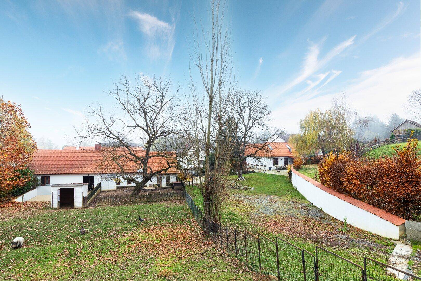 Weitläufiges Außengelände mit Rasenflächen, Bäumen und traditionellen Gebäuden im Hintergrund.