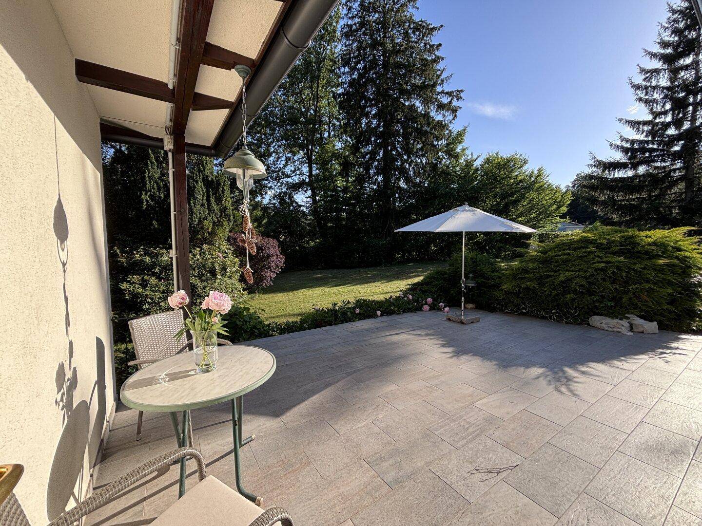 Geräumige Terrasse mit Sonnenschirm und Gartenmöbeln, ideal für entspannte Stunden im Freien.