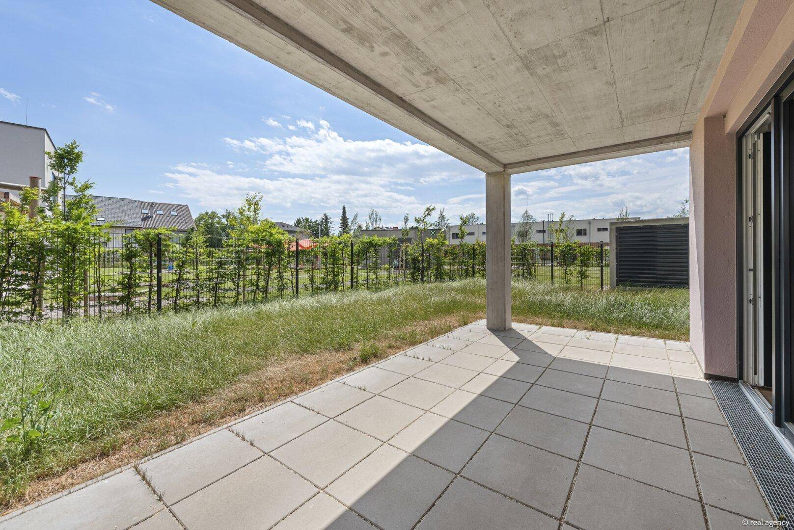 Geräumige, überdachte Terrasse mit Fliesenboden und weitem Blick über die grüne Umgebung.