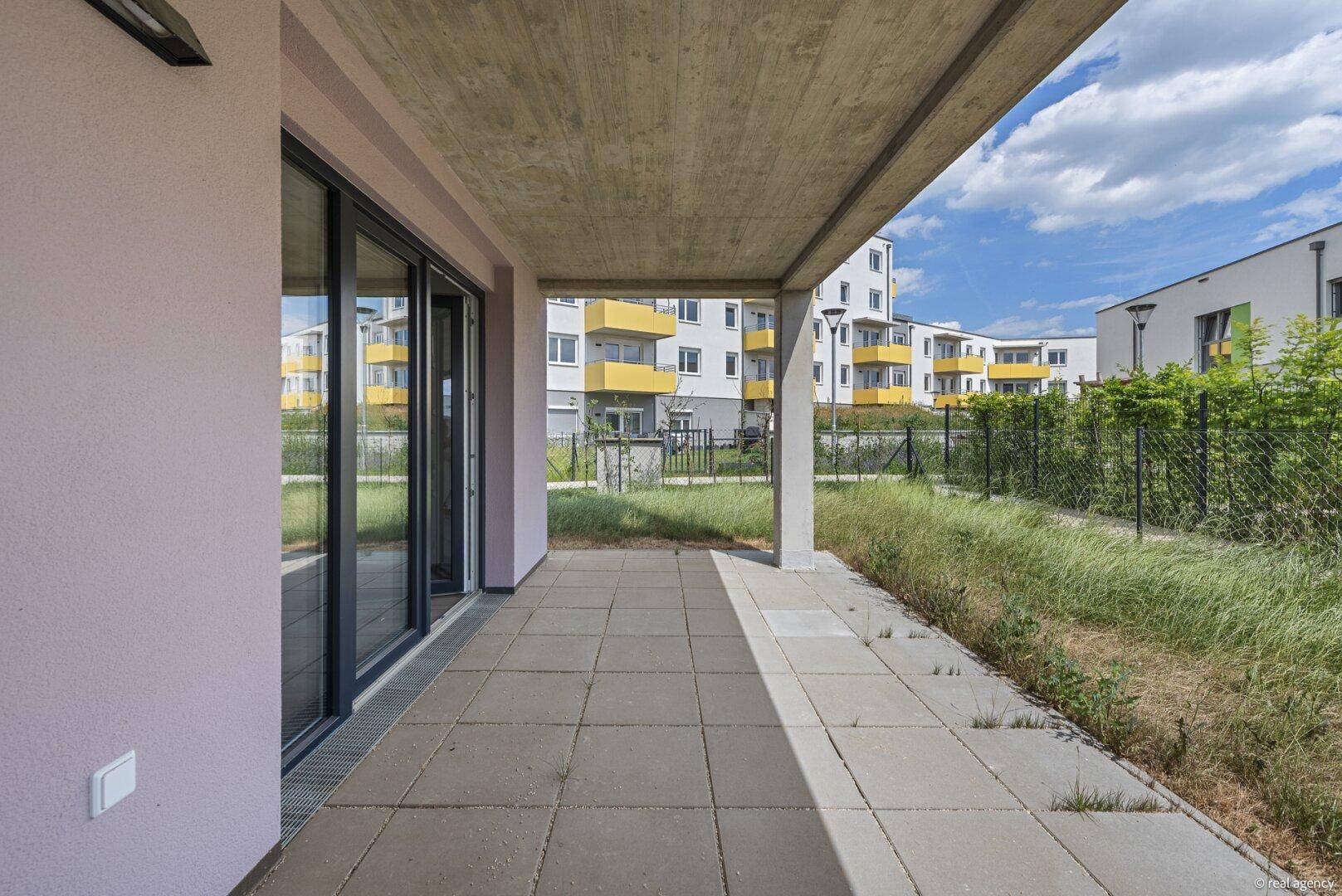 Geräumige, überdachte Terrasse mit Fliesenboden und großen Glasschiebetüren zum Wohnbereich.