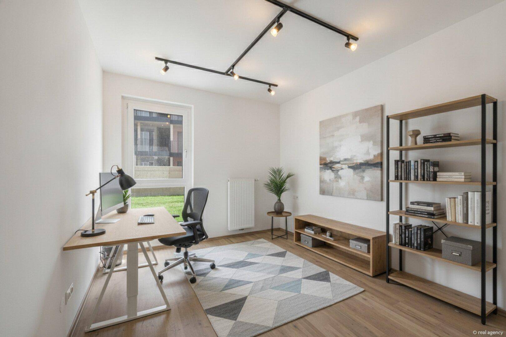 Modern eingerichtetes Arbeitszimmer mit Schreibtisch, Bücherregal und Blick ins Grüne.