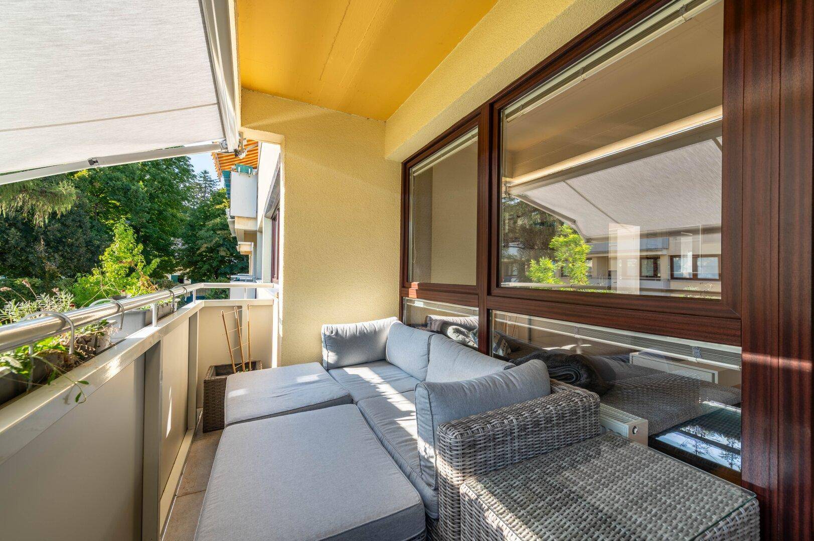 Gemütlicher Balkon mit Loungemöbeln und Blick ins Grüne.