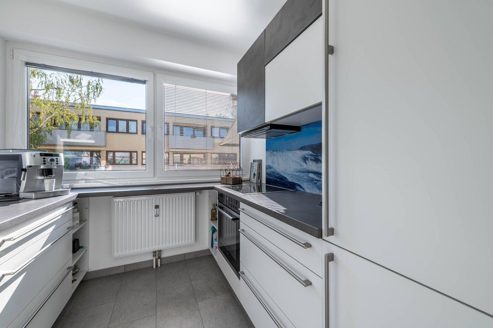 Helle Küche mit modernen Geräten, Fenster und Blick nach draußen.