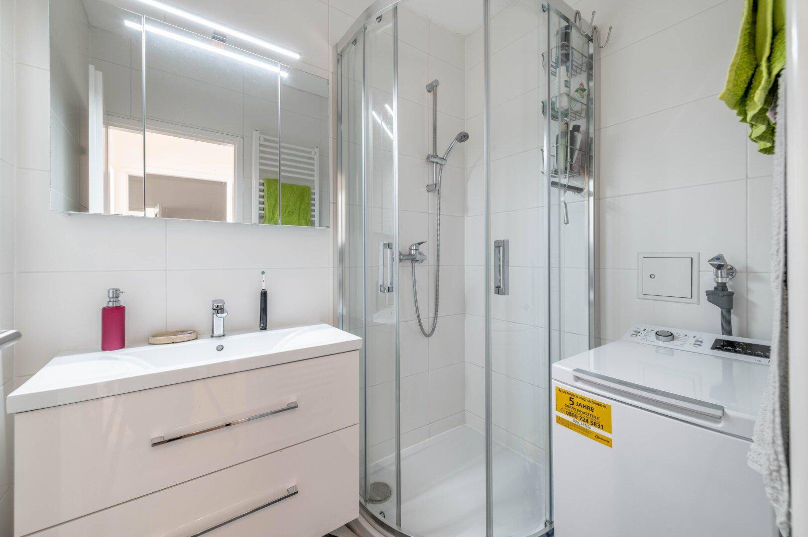 Modernes Badezimmer mit Dusche, Waschbecken und Waschmaschine.