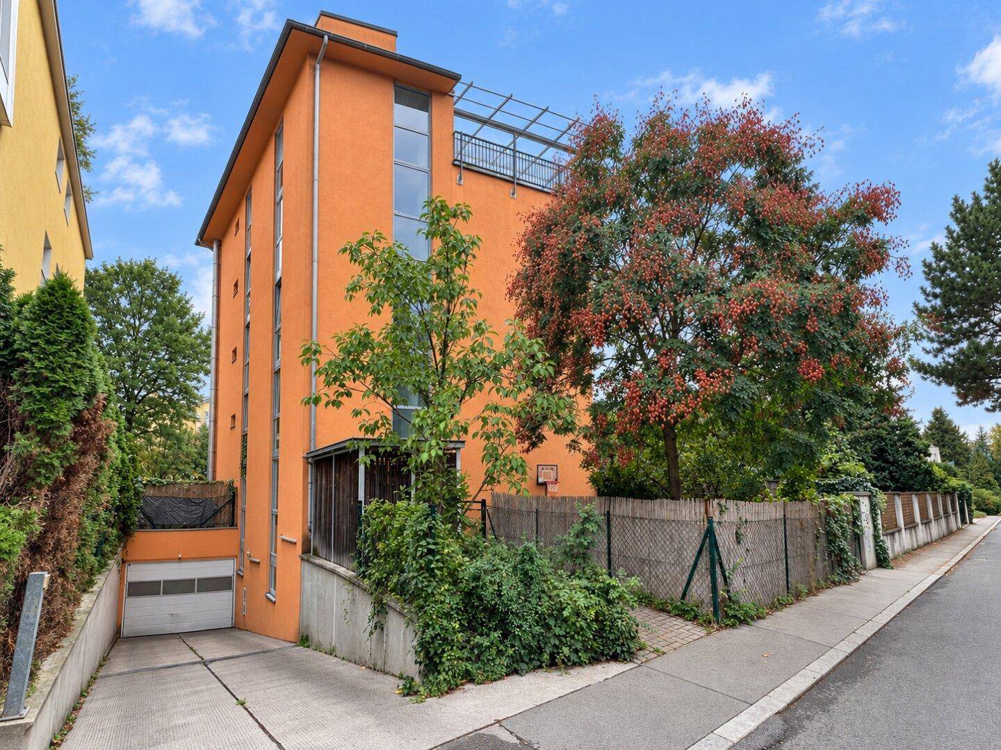 Mehrstöckiges Wohngebäude mit oranger Fassade und Garagenzufahrt.