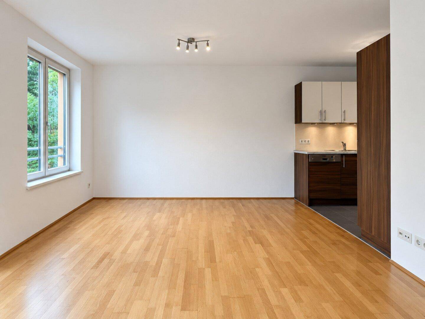 Geräumiger Wohnbereich mit Parkettboden und Blick auf die angrenzende, moderne Küchenzeile.