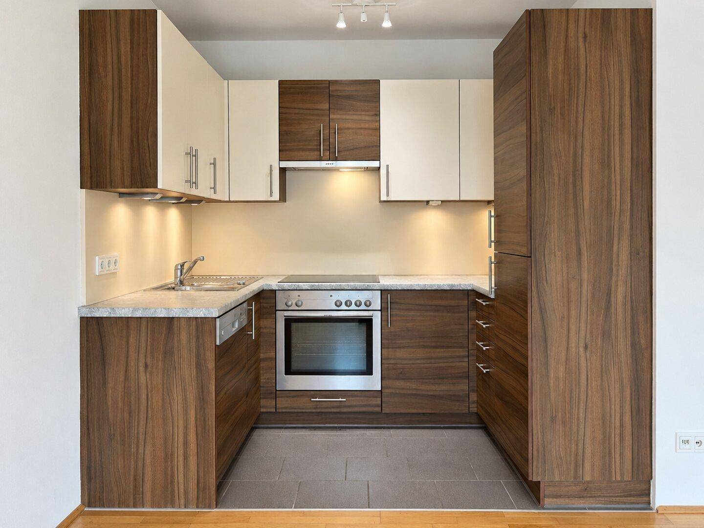 Moderne Einbauküche mit dunklen Holzfronten, hellen Oberschränken und integrierten Geräten.