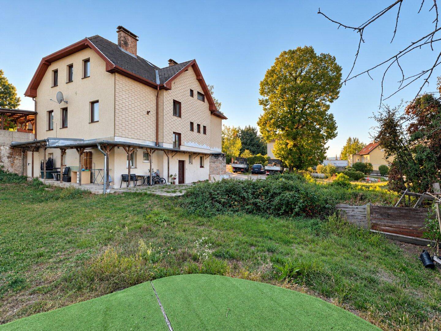 Großer Gartenbereich hinter dem Haus mit Rasenfläche, Bäumen und Blick auf die Umgebung.
