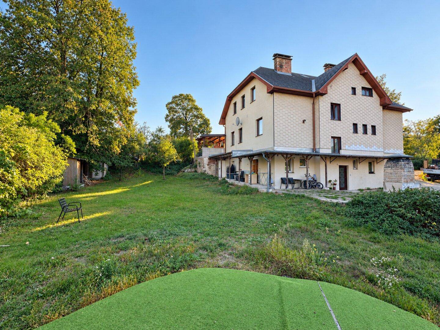 Weitläufiger Garten mit altem Baumbestand, Rasenfläche und Blick auf die Hausfassade.