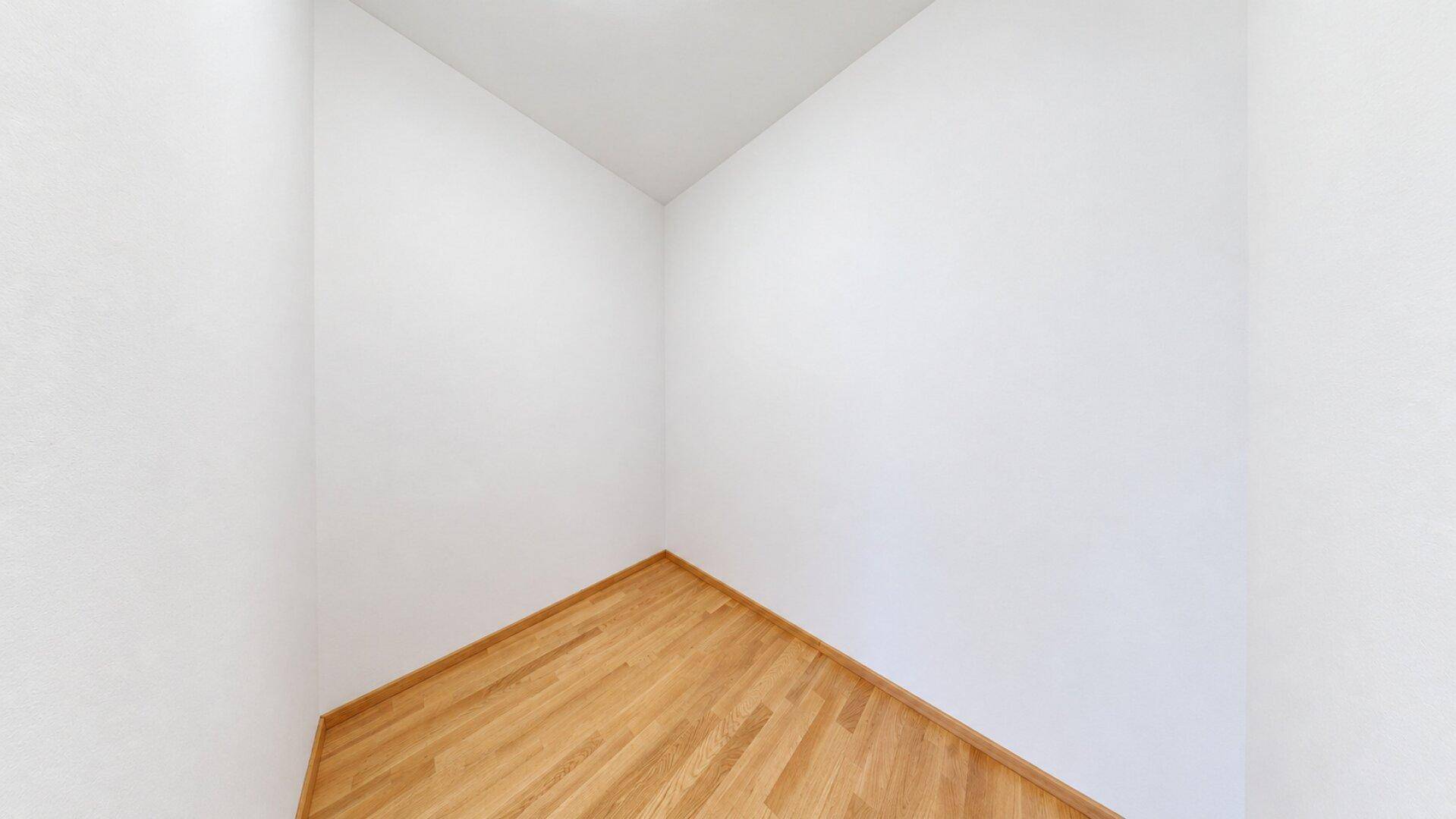 Kleiner, leerer Raum mit Holzboden und weißen Wänden, möglicherweise ein Abstellraum.