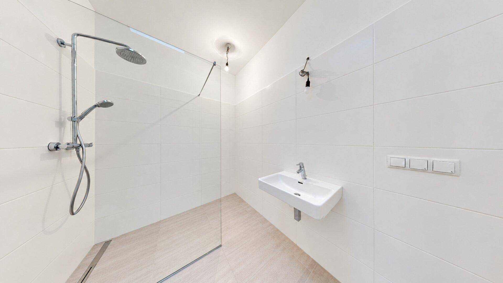 Modernes Badezimmer mit begehbarer Dusche, Einzelwaschbecken und weißen Wandfliesen.